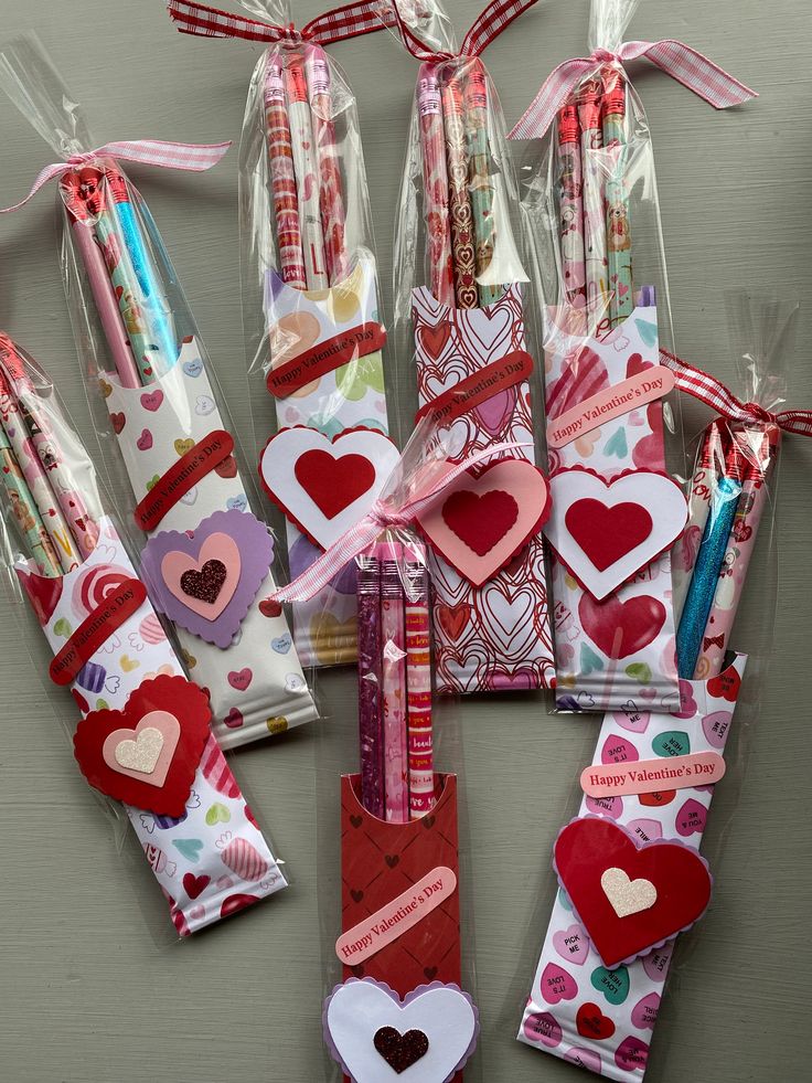 valentine's day candy wrappers and pencils are arranged in a heart pattern