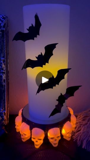 a lit up candle with bats on it and skulls in the foreground next to it