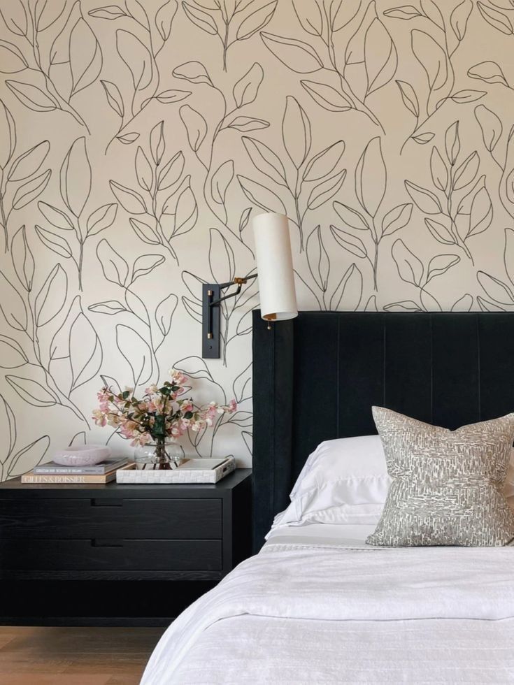 a bed with white sheets and pillows in front of a wallpapered bedroom area