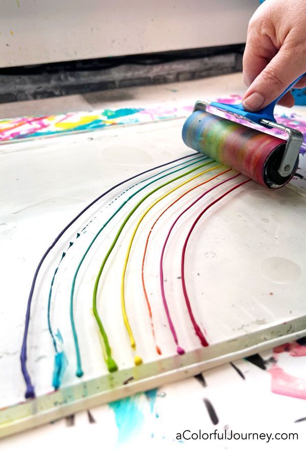 a person is painting on a table with paint rollers and watercolor paper in front of them