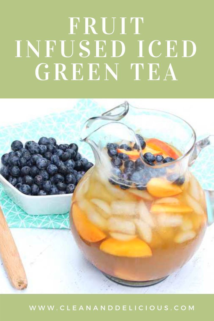 fruit infused iced green tea in a pitcher with blueberries and oranges on the side