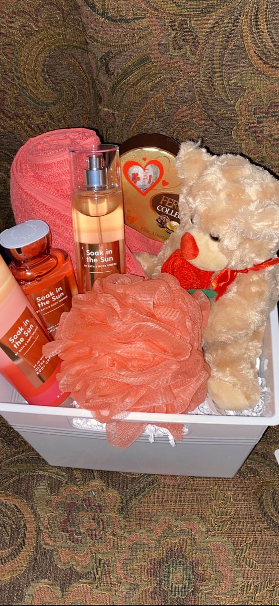 a teddy bear sitting in a white box filled with personal care items