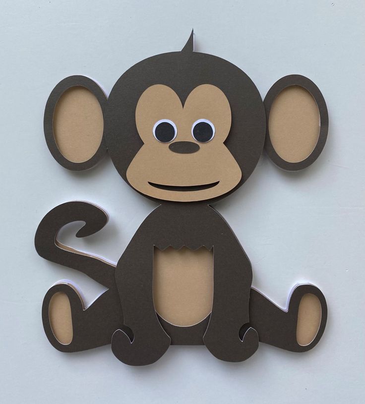 a paper cut out of a monkey sitting on top of a white surface with eyes wide open