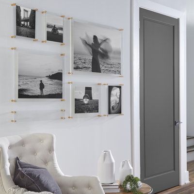 a living room with white walls and pictures on the wall above the couch, along with a chair