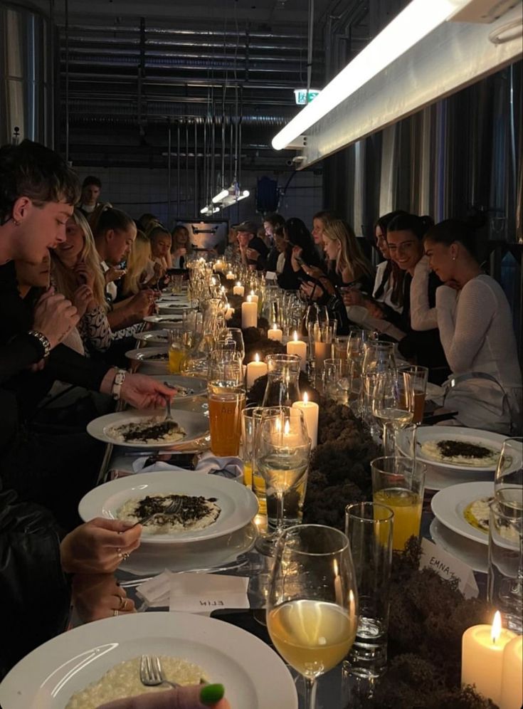 a group of people sitting at a long table with food and drinks