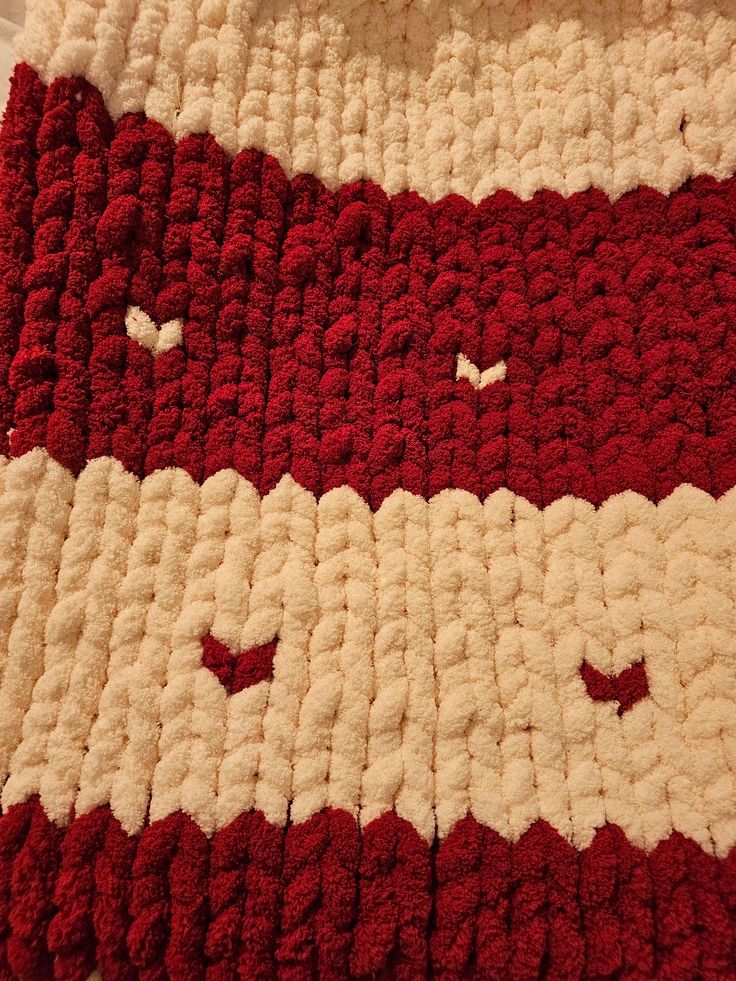 a red and white crocheted blanket on top of a bed