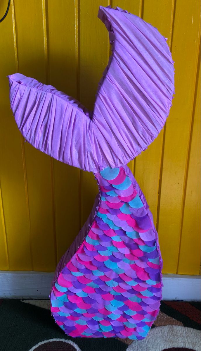 a purple and blue vase sitting on top of a rug next to a yellow door