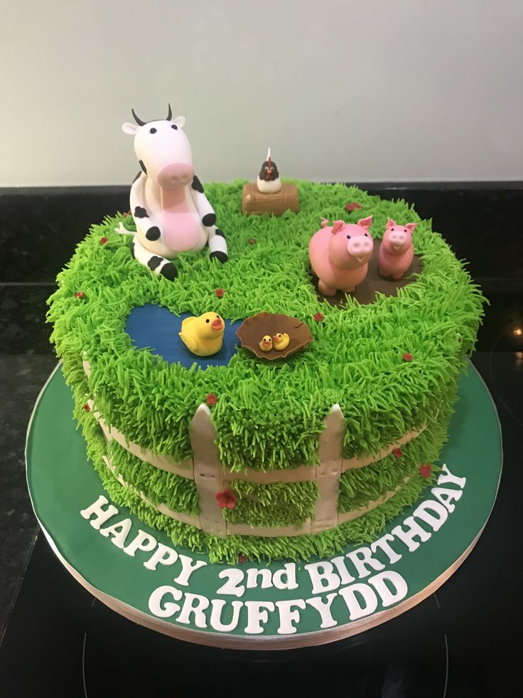 a birthday cake decorated with farm animals and grass