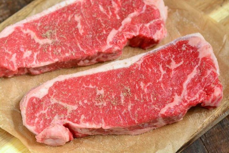 two pieces of raw meat sitting on top of a cutting board