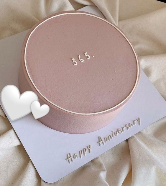 a pink cake on top of a white card with a happy anniversary written on it