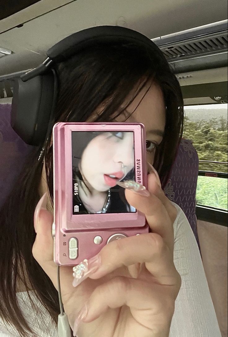 a woman with headphones is taking a photo on her cell phone in the car