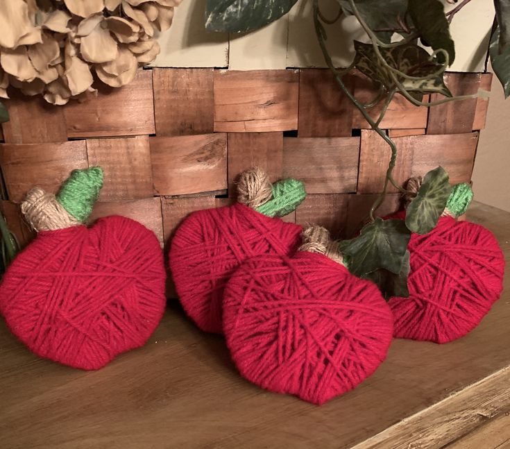 three red yarn pumpkins sitting on top of a wooden table