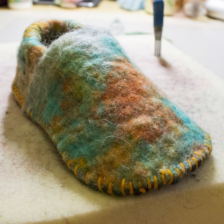 a pair of slippers sitting on top of a table next to a sewing needle