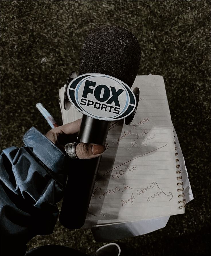 a person holding a microphone in front of a piece of paper with writing on it