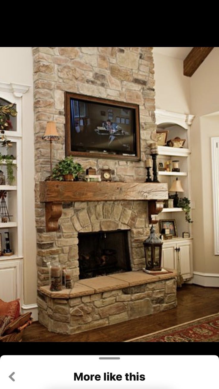 a living room with a stone fireplace and tv above the mantle, along with bookshelves