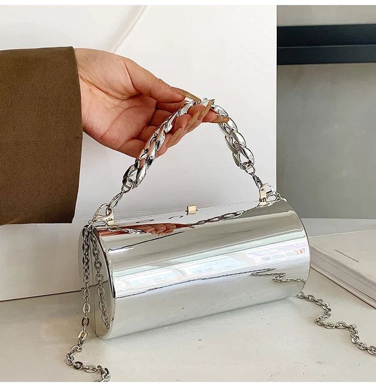 "The Cylinder Bag is the perfect statement accessory for any event. Its metallic design, available in silver or gold, adds a touch of sophistication. The large chain handle allows for easy carrying while keeping your essentials secure. Elevate your style with this elegant clutch purse." Cylinder Bag, Elegant Clutch, Belt Ring, Metallic Design, Cylinder Shape, Crossbody Clutch, Felt Bag, Evening Clutch Bag, Evening Clutch