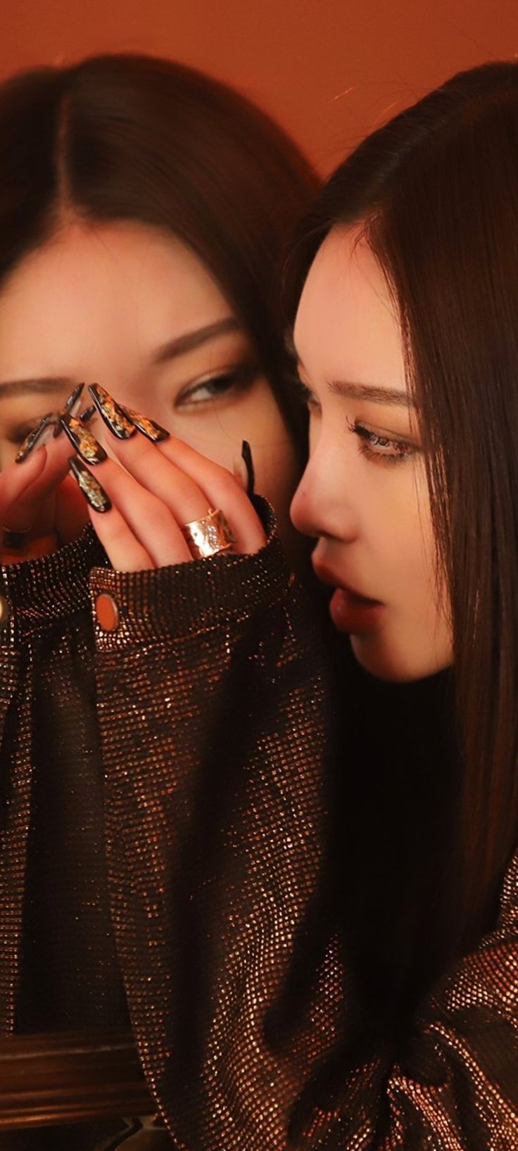 two young women looking at their nails in front of them, one holding the other's face