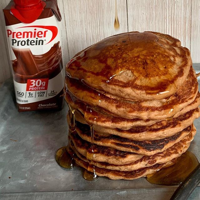 a stack of pancakes sitting on top of a counter next to a bottle of syrup