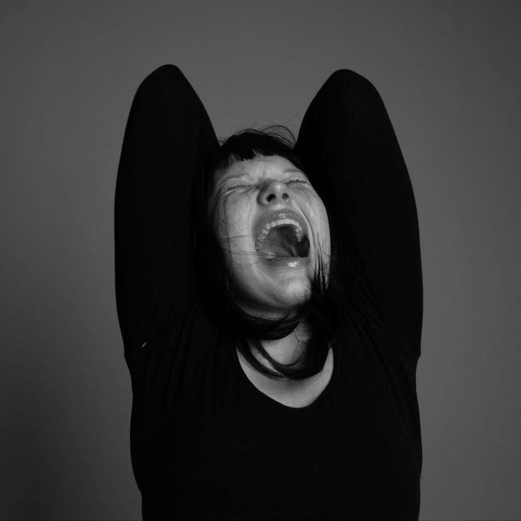 a woman with her mouth open and hands in the air above her head is screaming