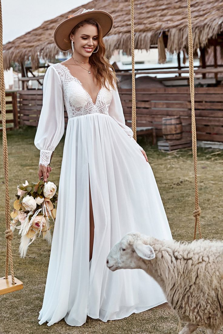 a woman in a white dress standing next to a sheep