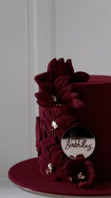 a close up of a red cake with flowers on the side and a happy birthday sticker