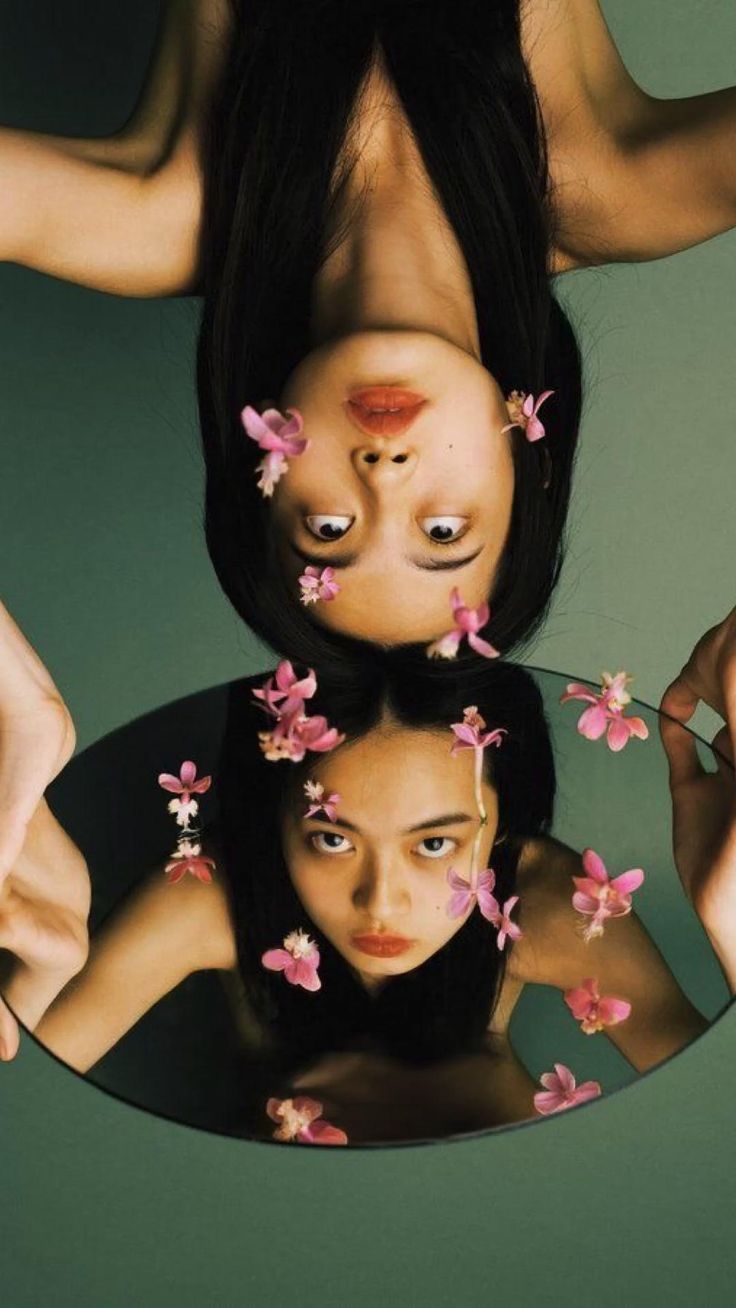 two women with flowers on their heads are reflected in a mirror that is upside down