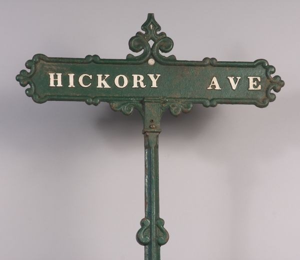 a green street sign that says hickory ave on it's pole with an ornate design