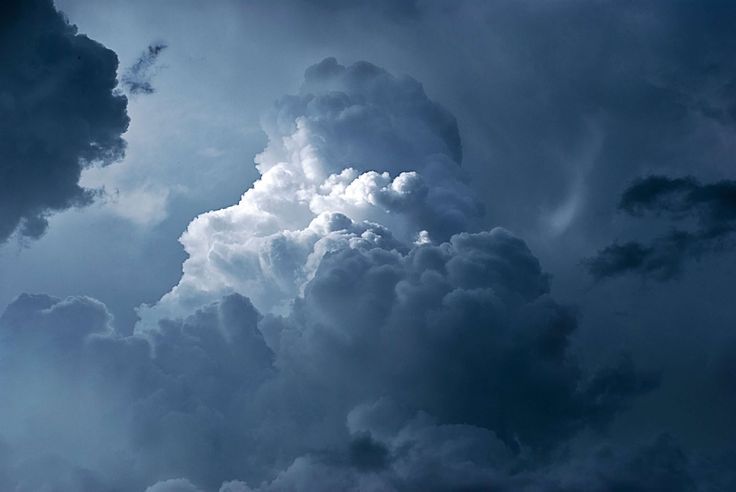 an airplane is flying in the sky with dark clouds behind it and sun shining through