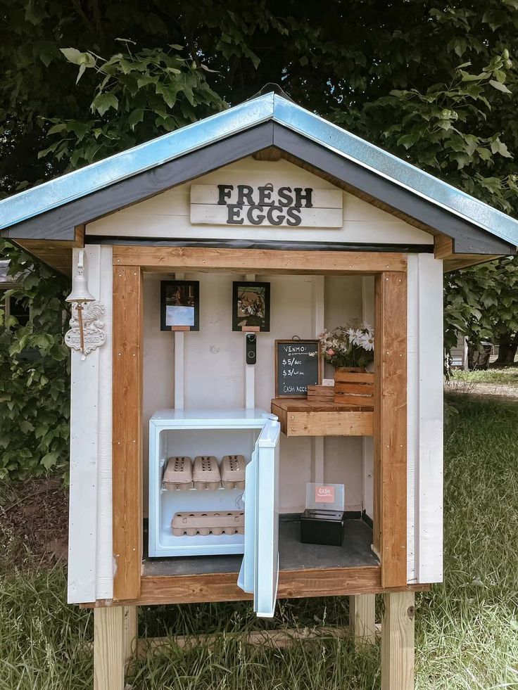 a small white and blue building with a sign on it's door that says fresh eggs