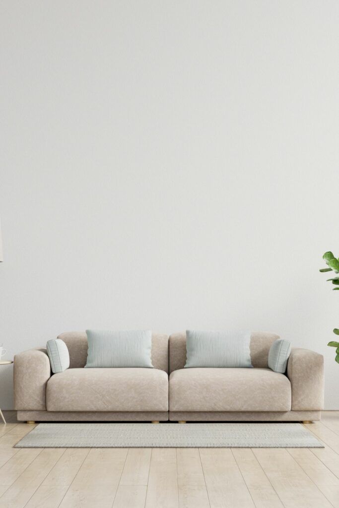 a living room with white walls and wooden flooring is pictured in this image, the couch has blue pillows on it