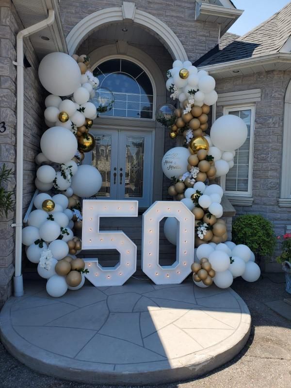 the front entrance to a house decorated with balloons and garlands for 50th birthday party