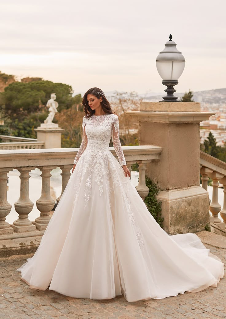 a woman in a white wedding dress standing on a balcony with her hand on her hip