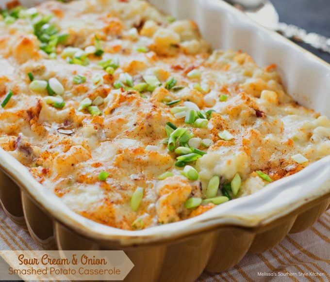 a casserole dish with green onions and cheese in it on a wooden table