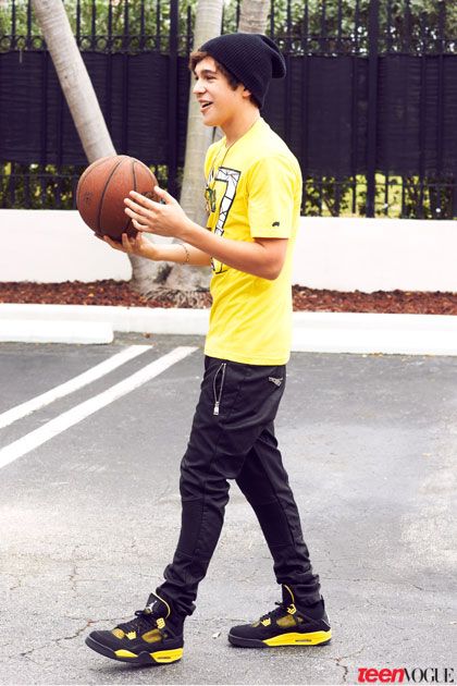 a young man holding a basketball in his right hand and wearing black pants with yellow shoes