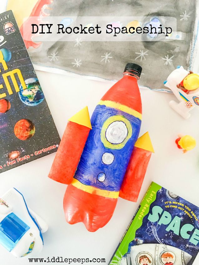 an orange and blue rocket ship sitting on top of a white table next to books