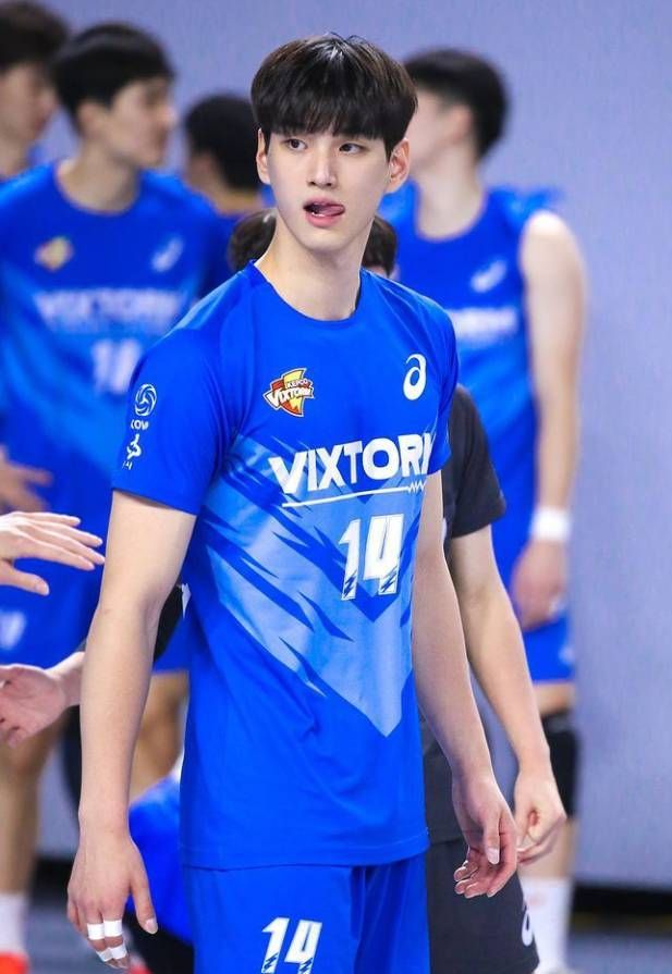 a young man in blue uniform standing next to other men wearing blue uniforms and talking