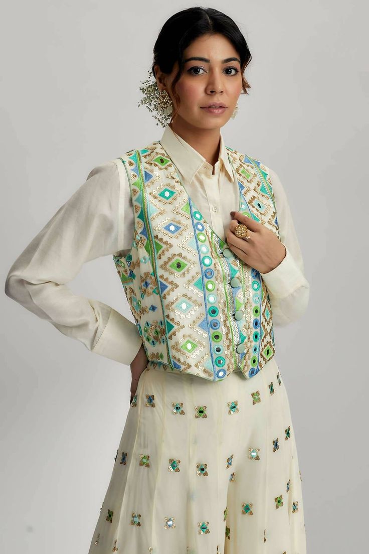 Introducing the exquisite amara jacket set with flared pants, a stunning ensemble that combines traditional craftsmanship with contemporary design. This ensemble features intricate mirror work, pompoms and tassels, along with detailed hand and machine embroidery, making it a true work of art. Elegant Nehru Jacket With Gota Work For Festive Occasions, Festive Embellished Multicolor Embroidered Sharara, Festive Embellished Multicolor Embroidery Sharara, Bohemian Sets With Gota Work For Eid, Bohemian Gota Work Sets For Eid, Bohemian Embroidered Palazzo Set, Festive Multicolor Embroidered Palazzo Set With Mirror Work, Bohemian Sharara With Mirror Work For Eid, Bohemian Embellished Palazzo Set For Navratri