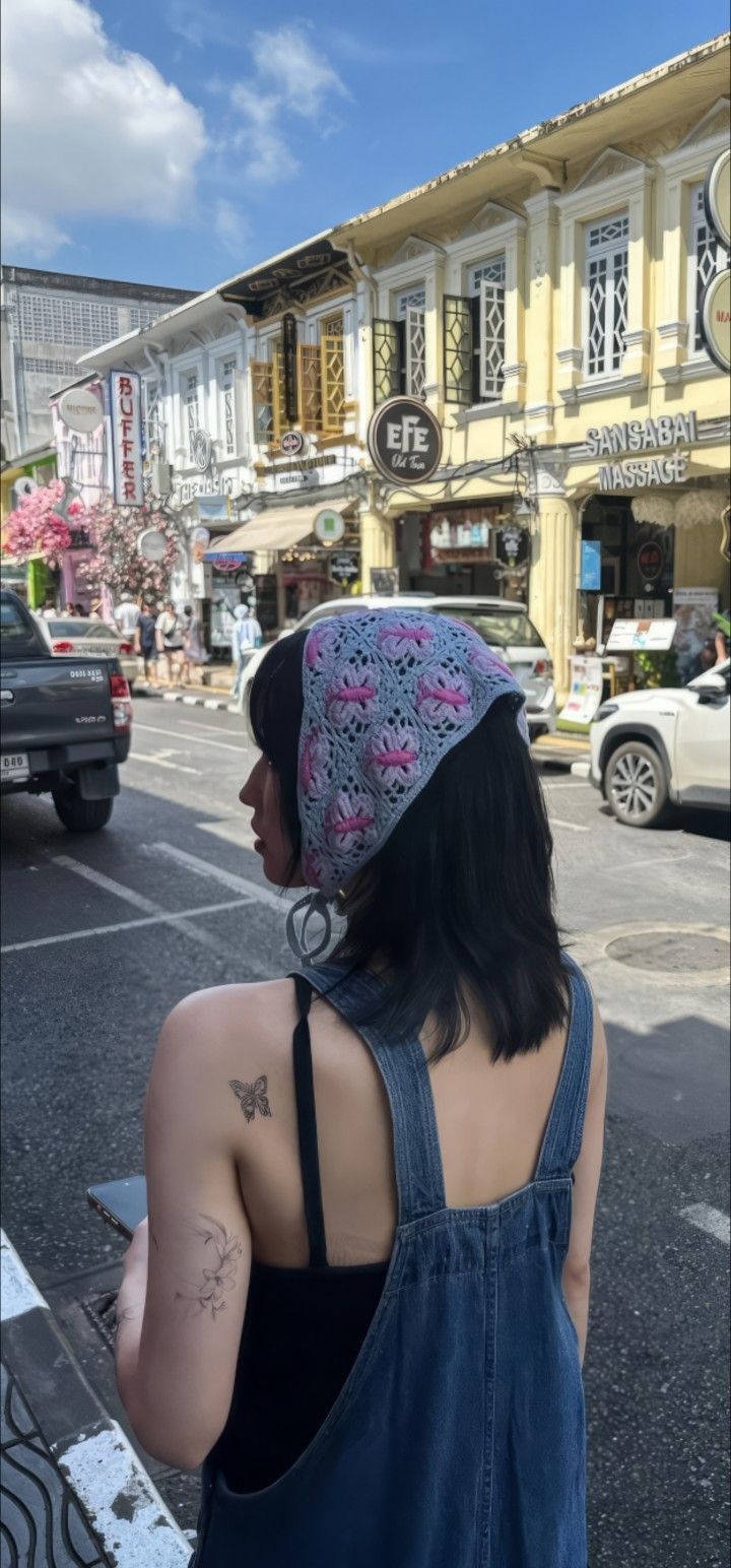 a woman in overalls and a knitted hat is looking at the street corner