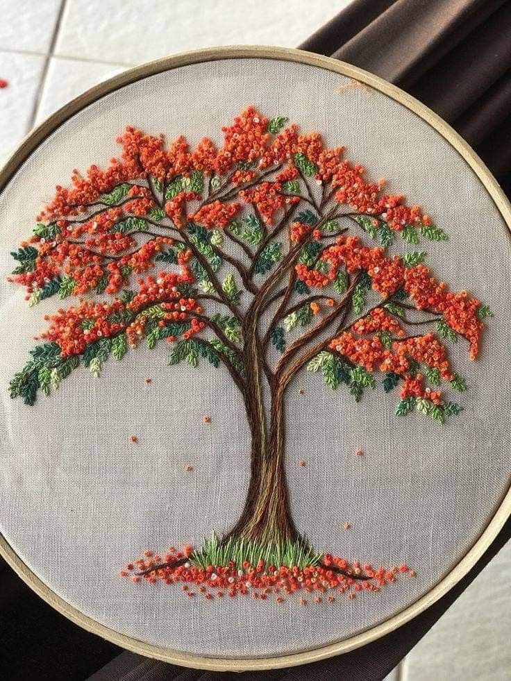 an embroidered tree with red flowers on it