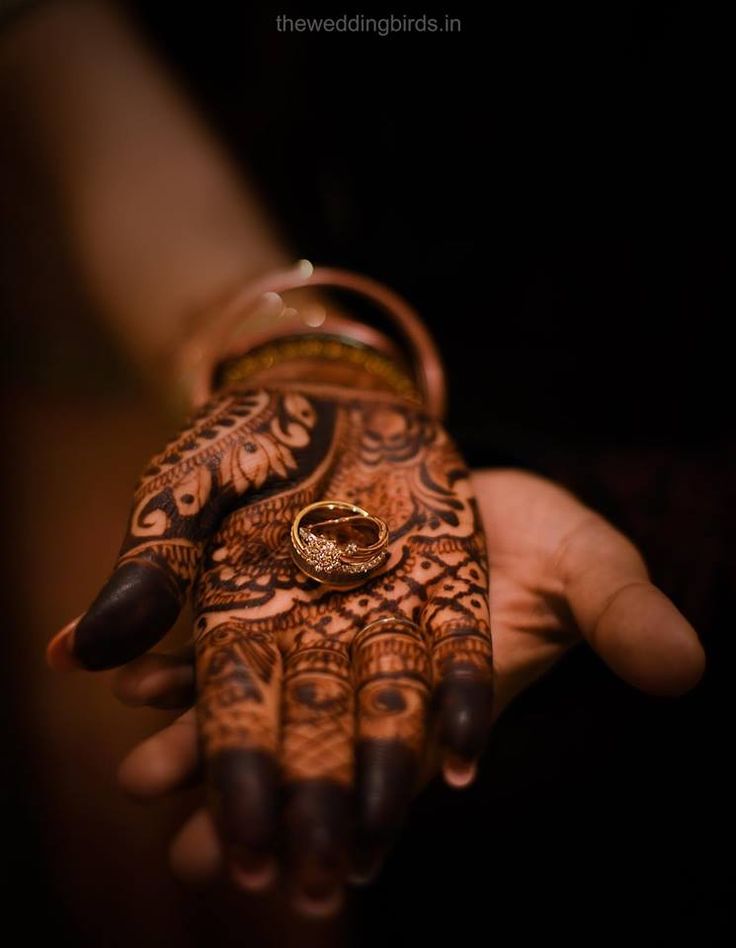 a person's hand with henna and ring on it