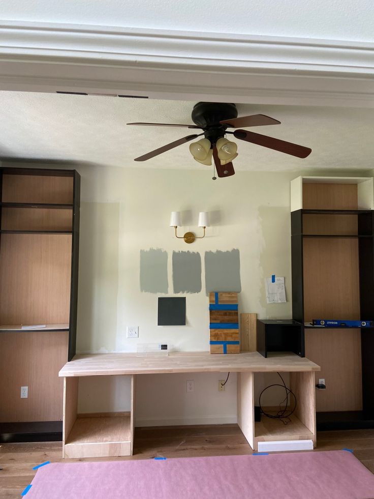 an empty room with some paint on the walls and a ceiling fan in the middle