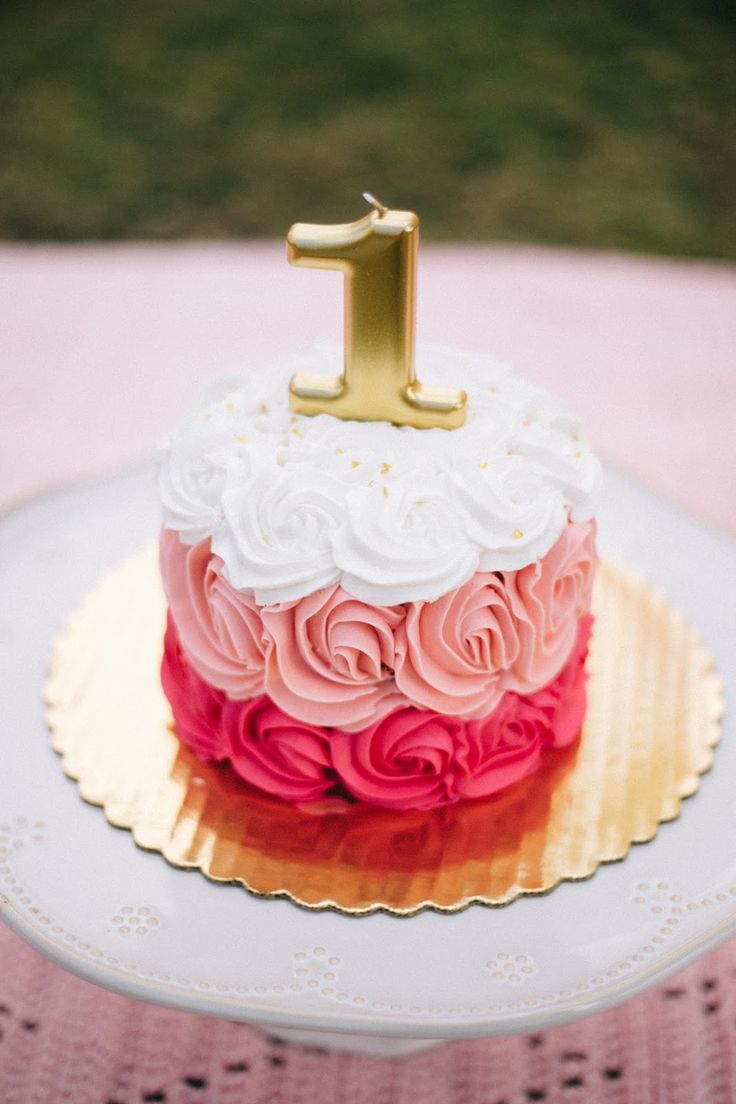 a pink and white cake with a gold one on top