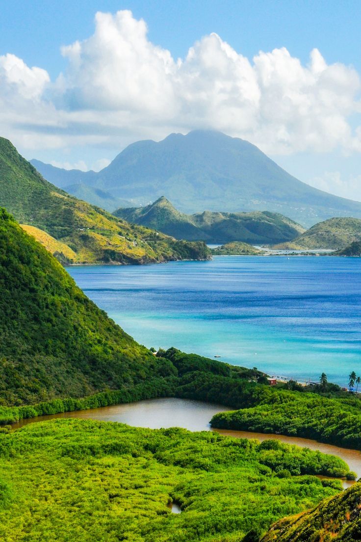 the ocean is surrounded by lush green hills and blue water with mountains in the background