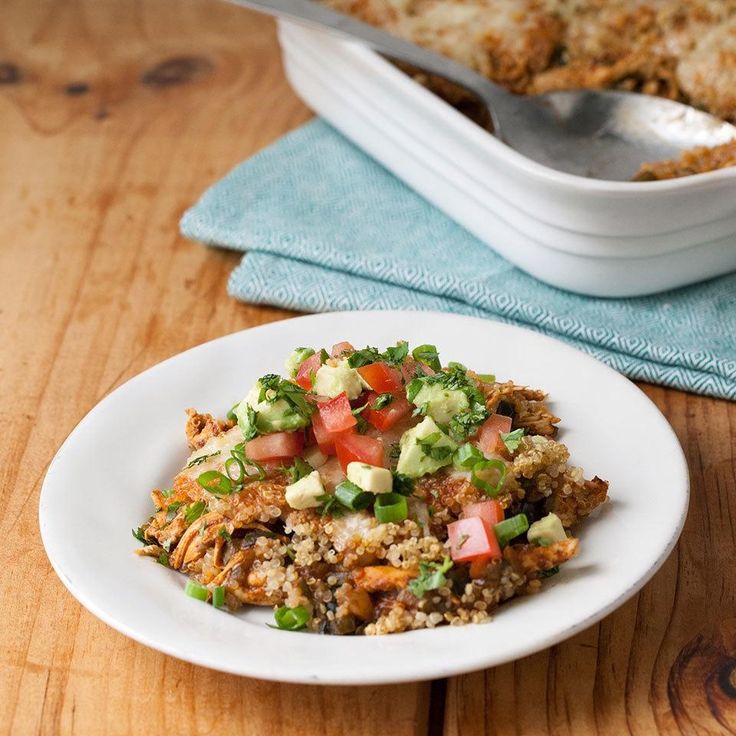 a white plate topped with food next to a casserole filled with meat and veggies