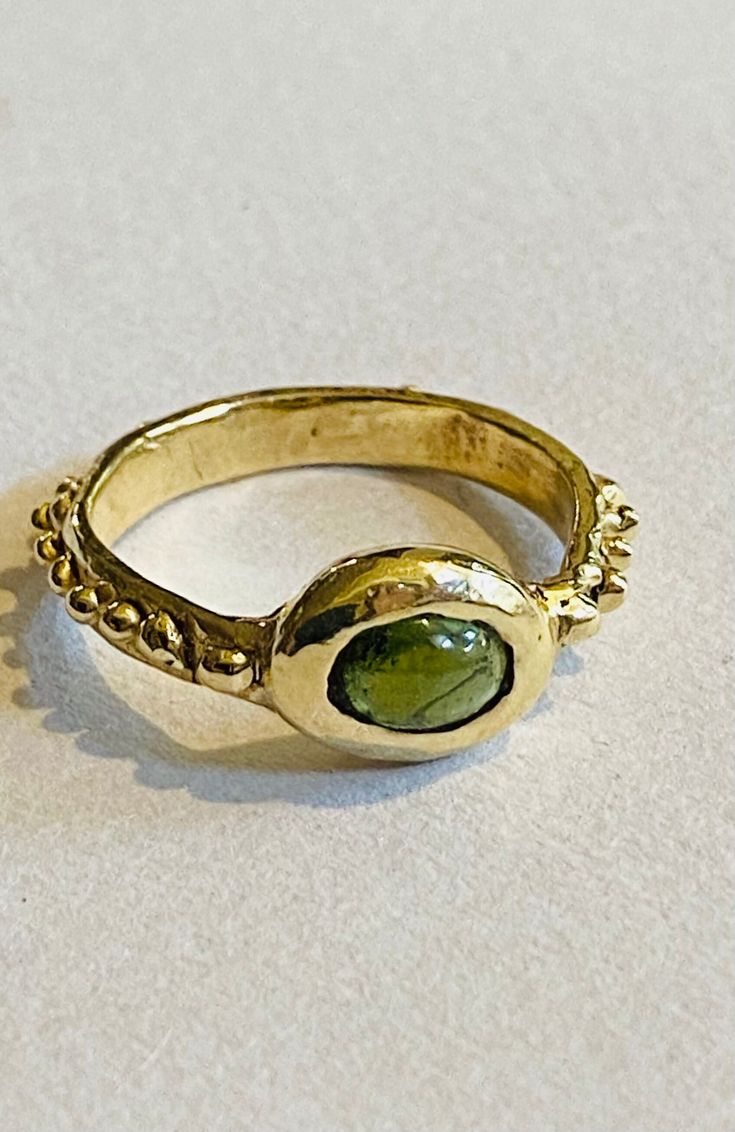 A solid nine carat gold ring with a green cabochon cut tourmaline is handmade and one of a kind . This rustic romantic style features detailing around the band and it is perfectly imperfect - a fluid organic yet luxurious piece .UK/AU N -US 6 3/4 Tourmaline Bezel-set Oval Cabochon Ring, Tourmaline Bezel Set Ring In Oval Cabochon, Tourmaline Ring With Bezel Setting In Oval Cabochon, Gold Tourmaline Ring For May Birthstone, Yellow Gold Tourmaline Cabochon Ring, Oval Tourmaline Emerald Ring With Bezel Setting, Handmade Tourmaline Gold Ring, Handmade Gold Tourmaline Ring, Etsy Gold Ring