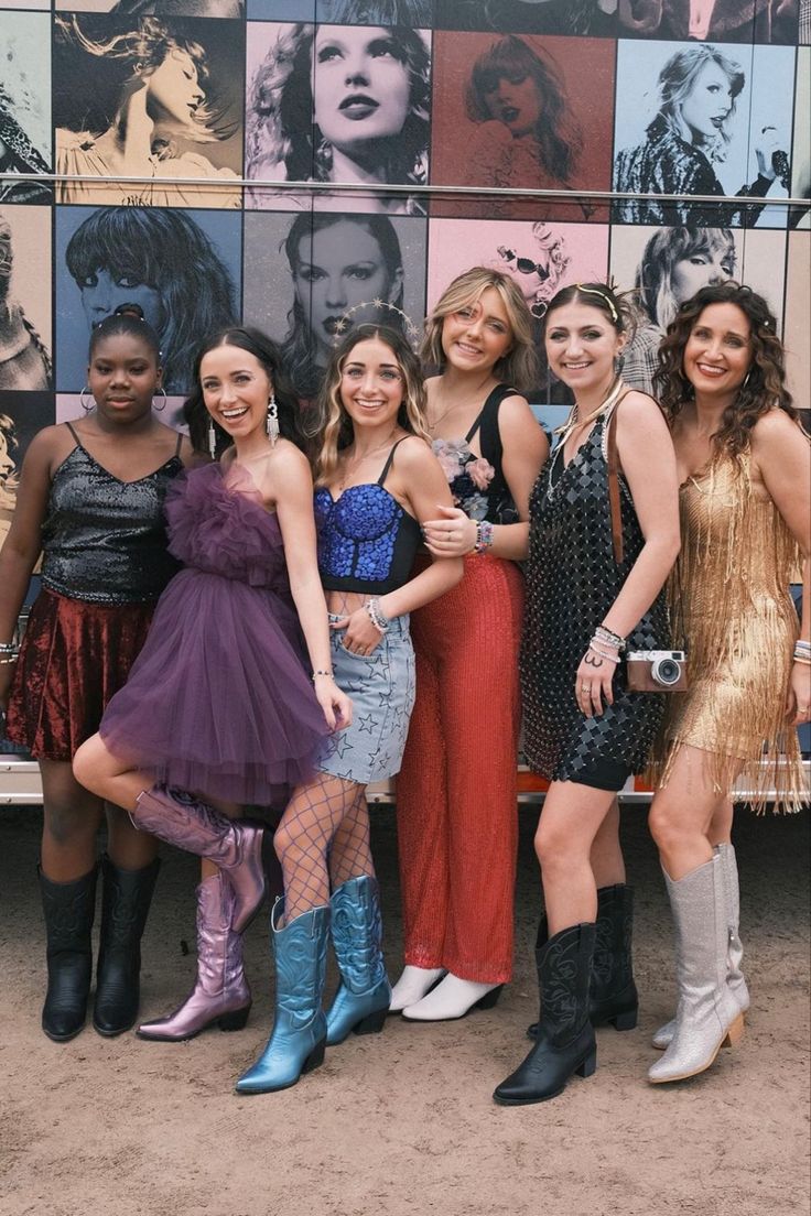 a group of women standing next to each other in front of a wall with pictures on it