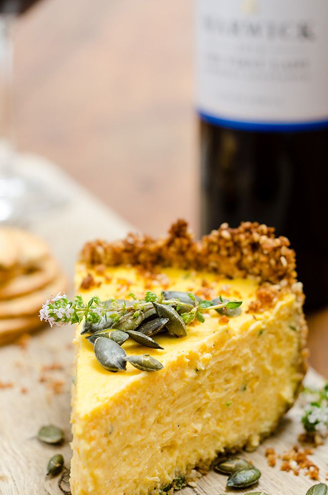 a slice of cheesecake on a cutting board next to a bottle of wine