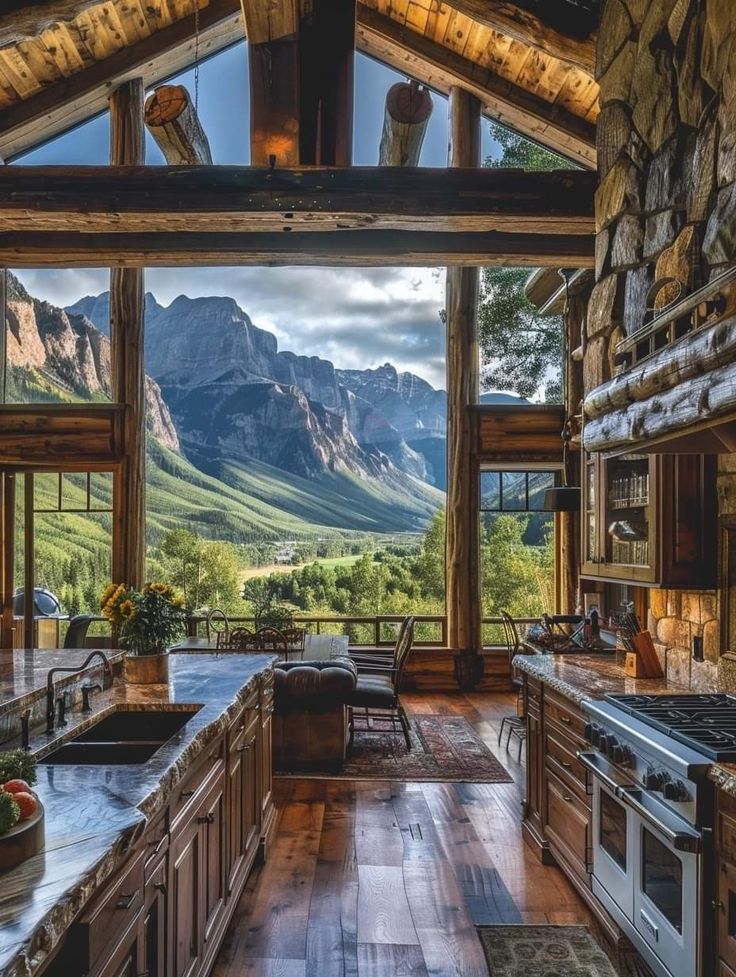 an open kitchen with mountains in the background and wood flooring, along with large windows on both sides