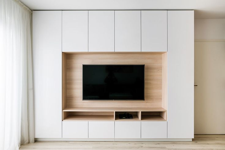 an entertainment center with a flat screen tv mounted on it's side, in front of a white wall