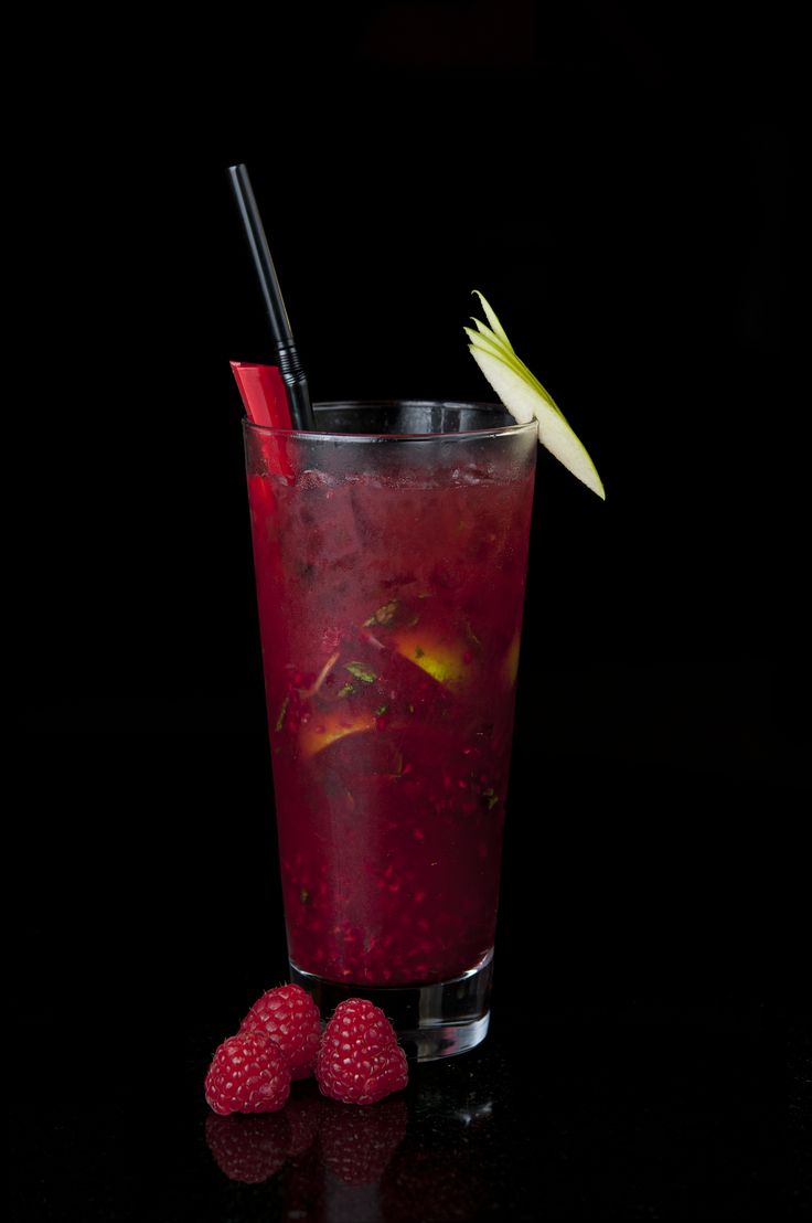 raspberry lemonade cocktail in a tall glass with two strawberries on the side